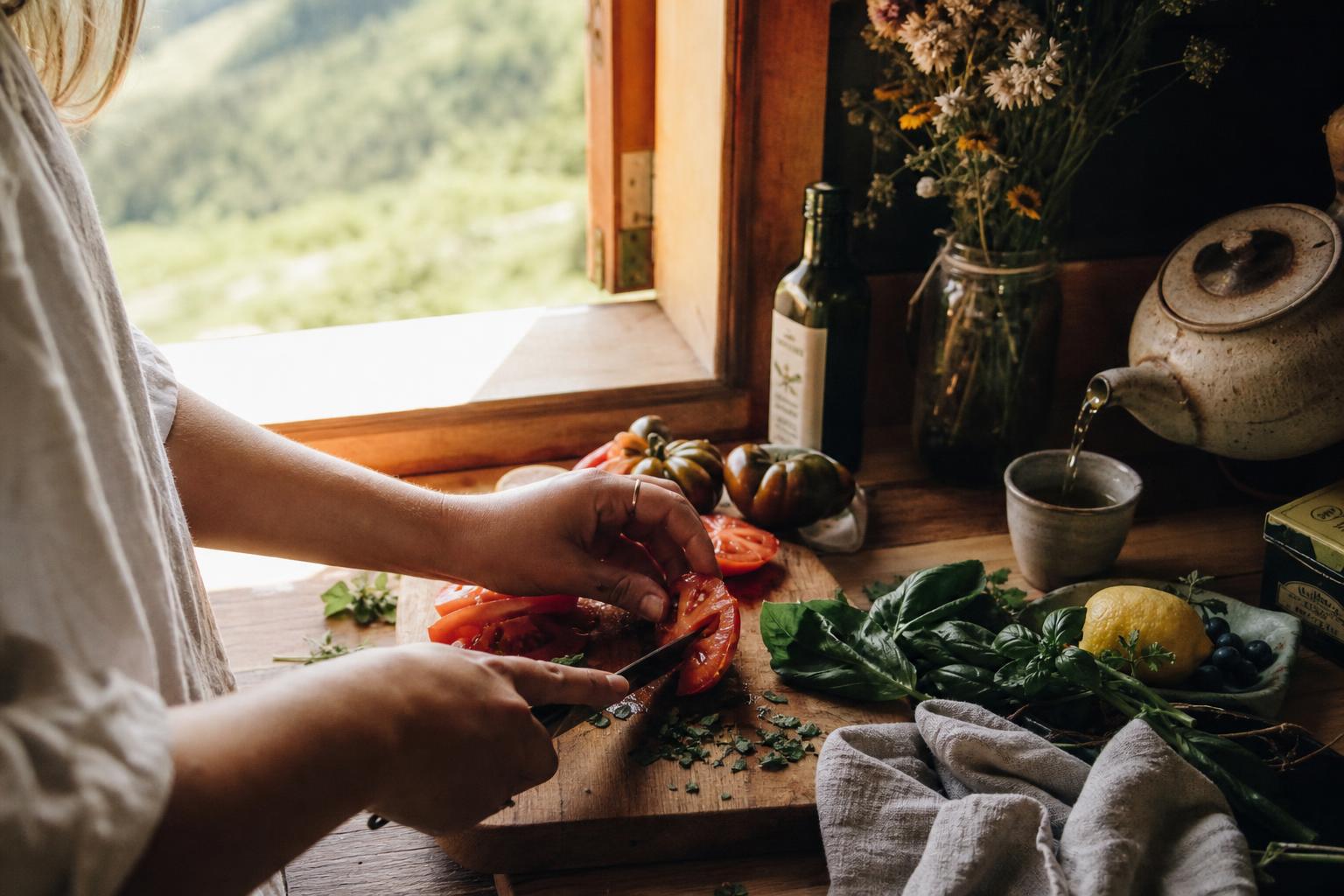 Colorful fresh whole foods, herbal tea, and wildflowers on a rustic wooden table by a sunlit mountain window