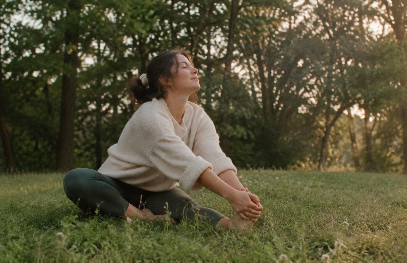 Person stretching slowly and breathing outdoors in warm evening light